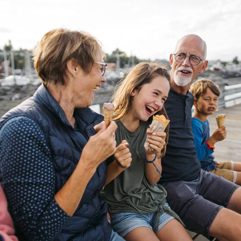 grandparents sitting down with grandchildren outside eating ice cream cones